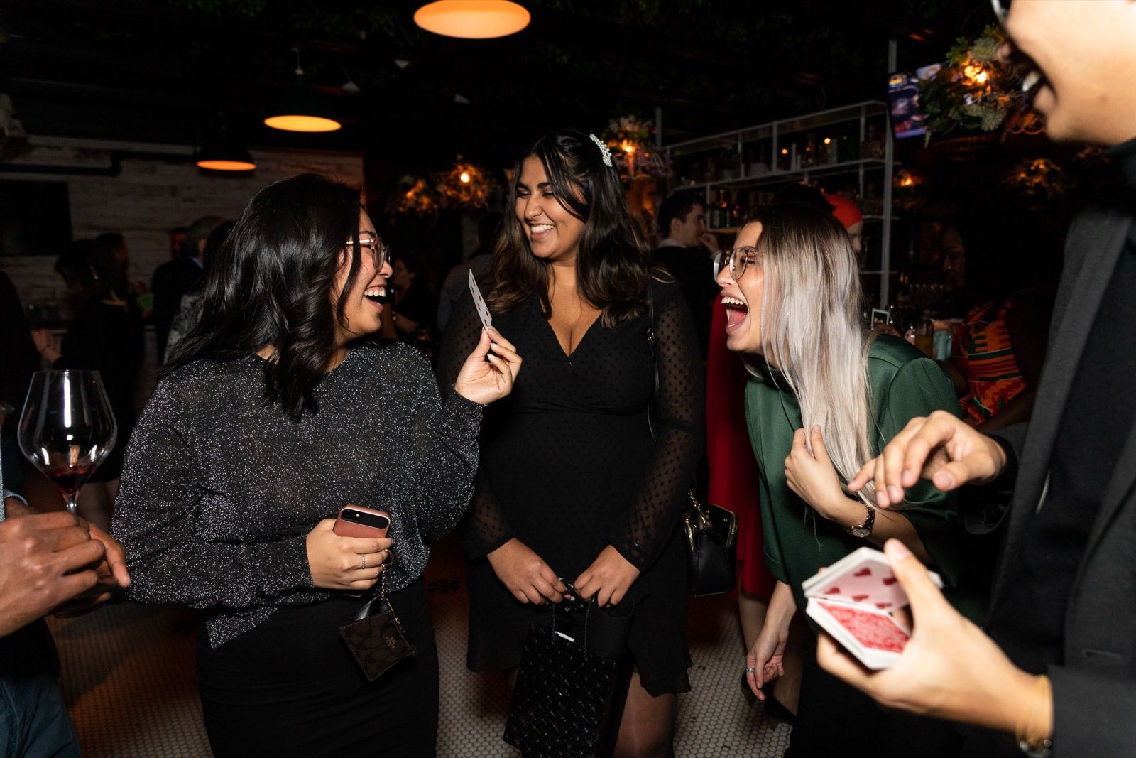 Three guests burst out laughing as Bao reveals a chosen card during a party