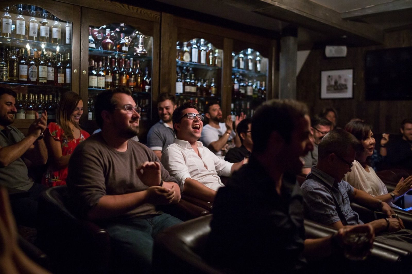 A small room of guests laughing together during an intimate performance by Bao