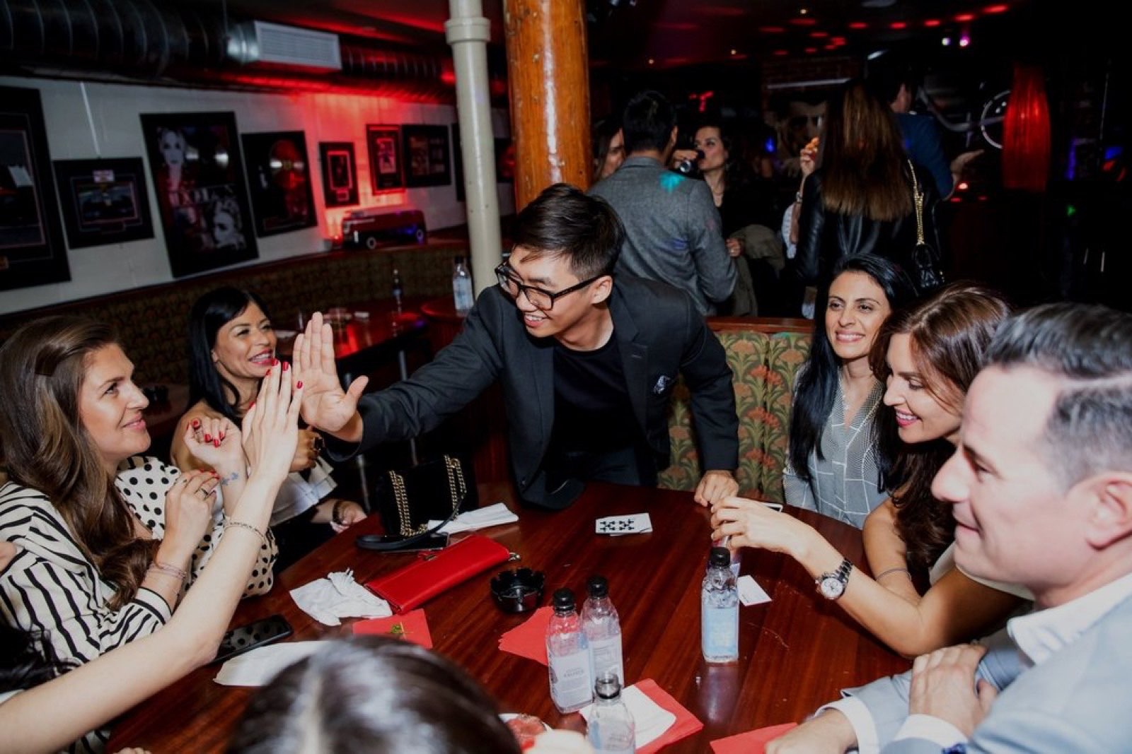 Bao high-fives a table of delighted guests during an intimate dinner performance